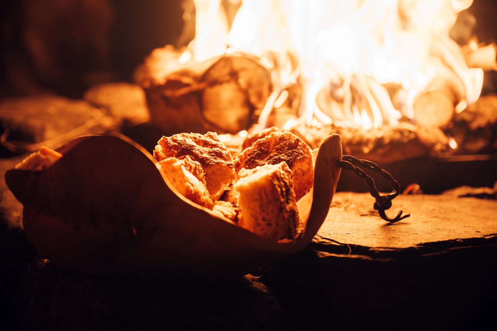 Bread bowls in a wooden dish on the stones, the fire behind