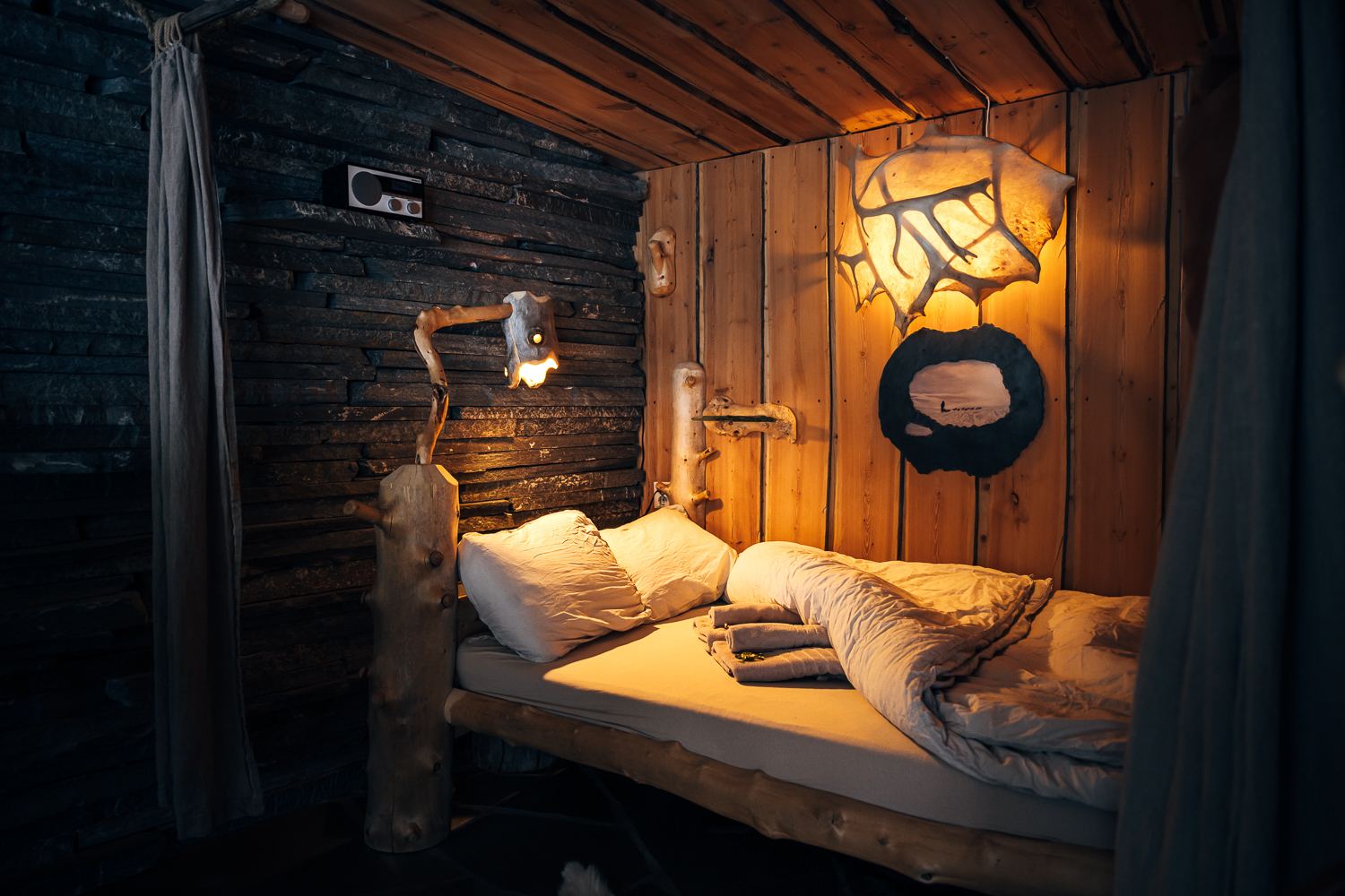 A sleeping alcove with lamplight and white linen