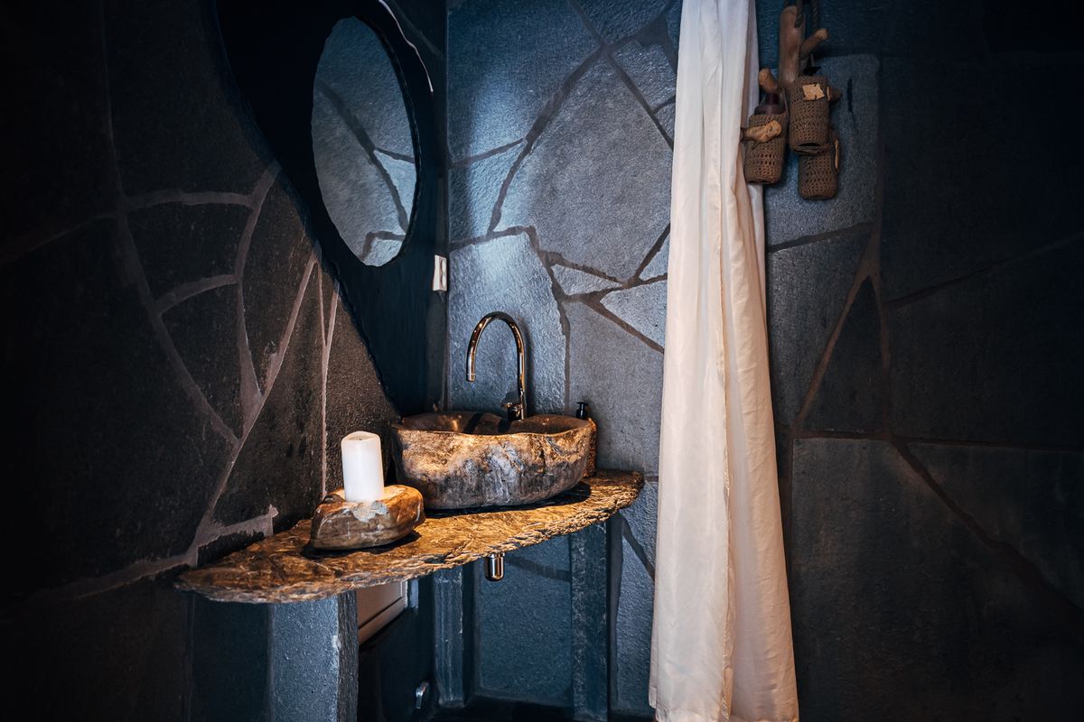 A stone basin on a slate wall with a candle