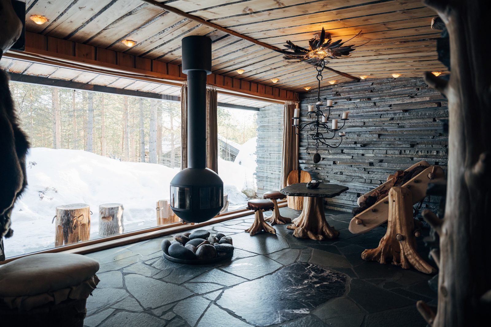 Buvri's main room: slate floor, hanging stove and a wall of glass