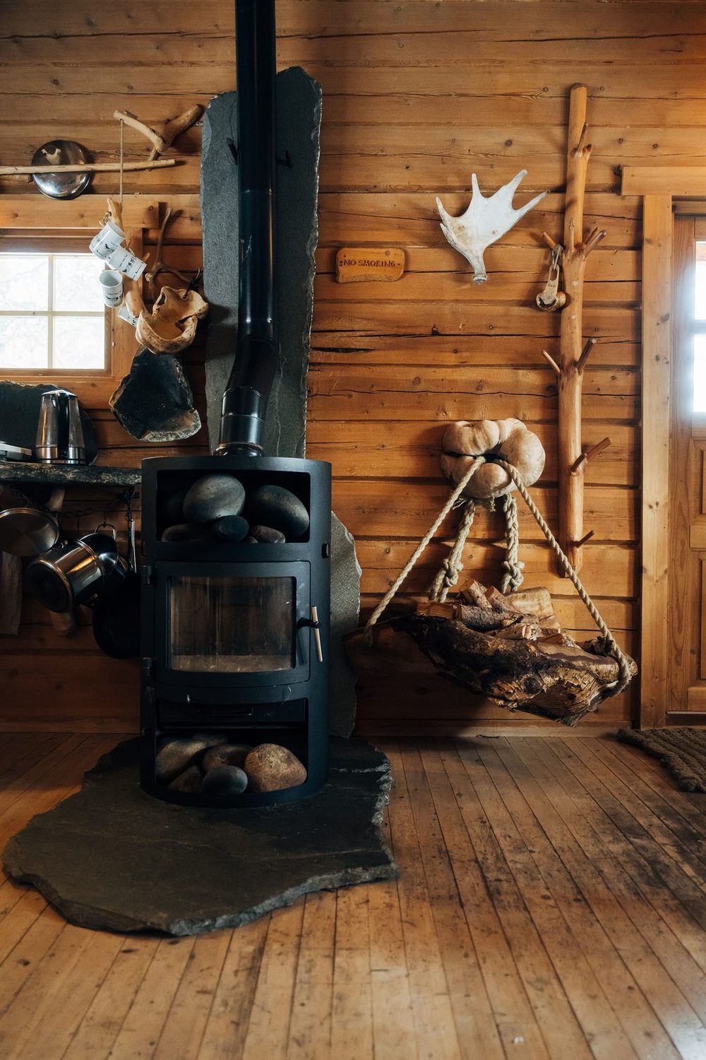 The black stove with antlers and tools hung on the log wall