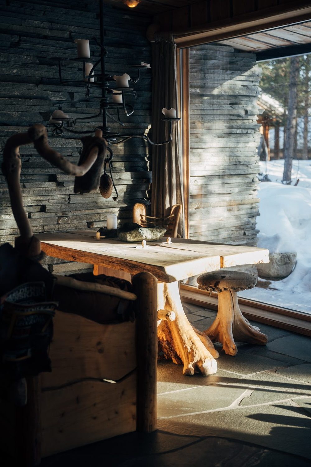 The dining table by the slate wall, a lamp hanging over it and the window beside