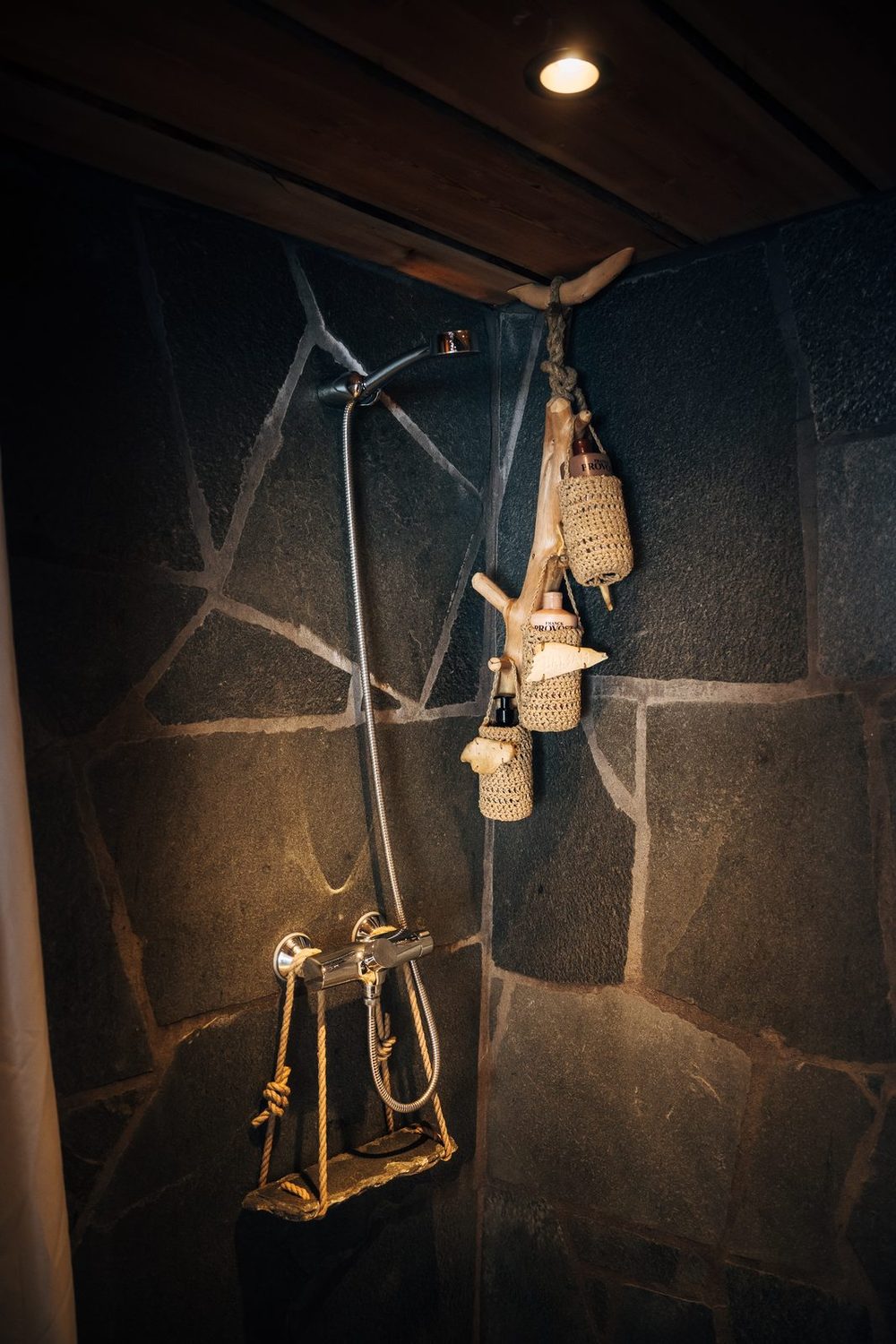 The shower against a wall of slate, a lamp on a rope beside it