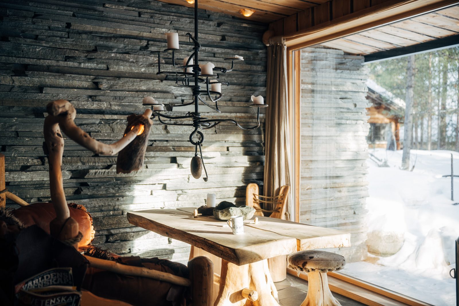 The table under a hanging lamp with the wall of glass and snow behind it