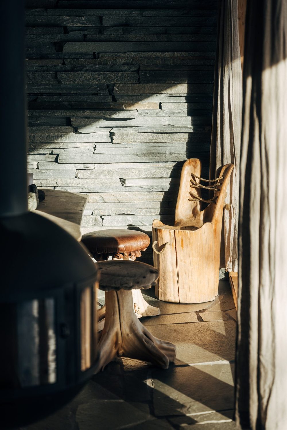 The black stove and a carved chair against the slate wall