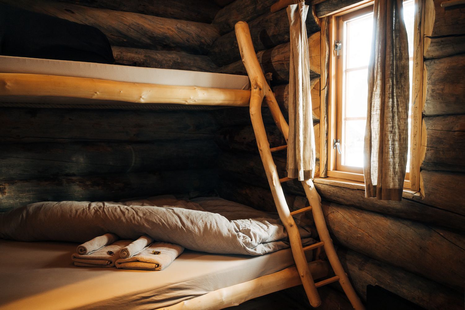 A bunk with a birch ladder beside the window