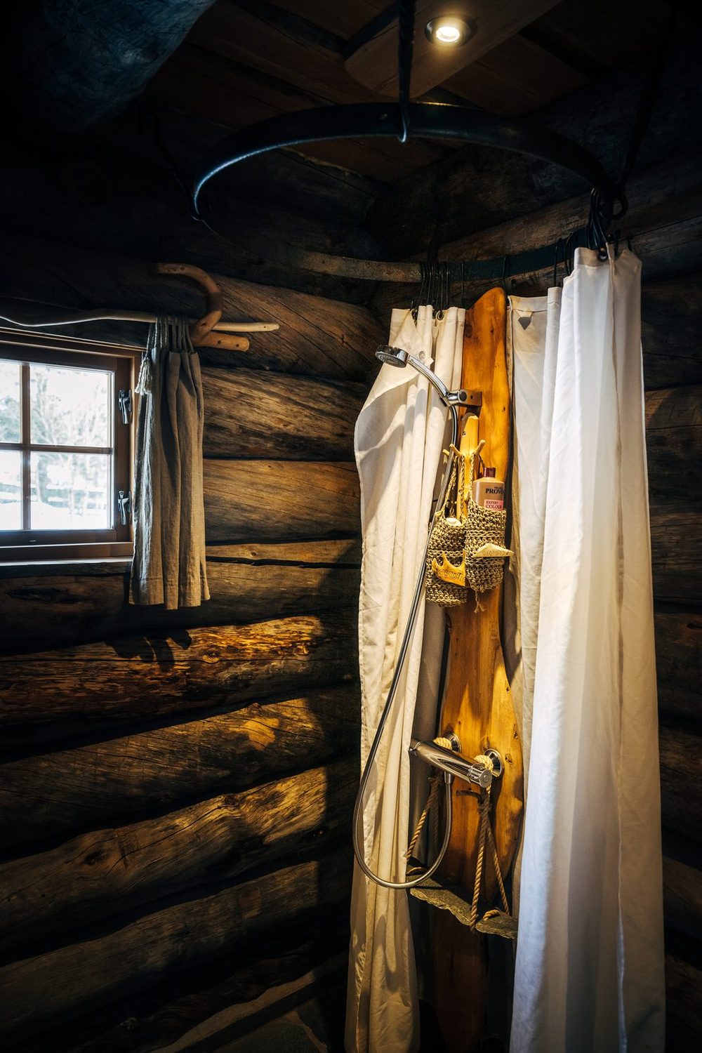 The shower behind a white curtain by a small window