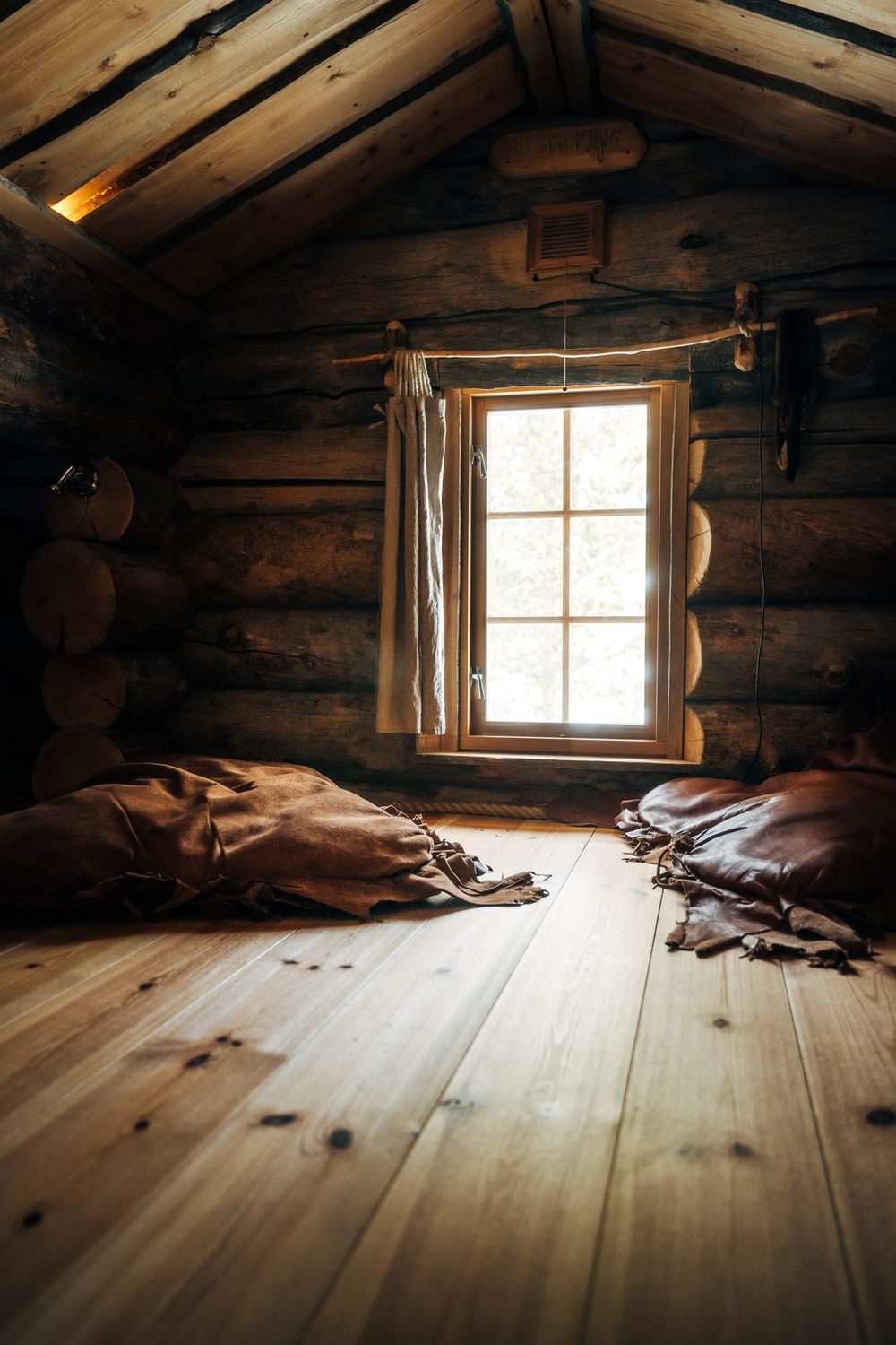Reindeer hides laid out under the window on the wooden floor