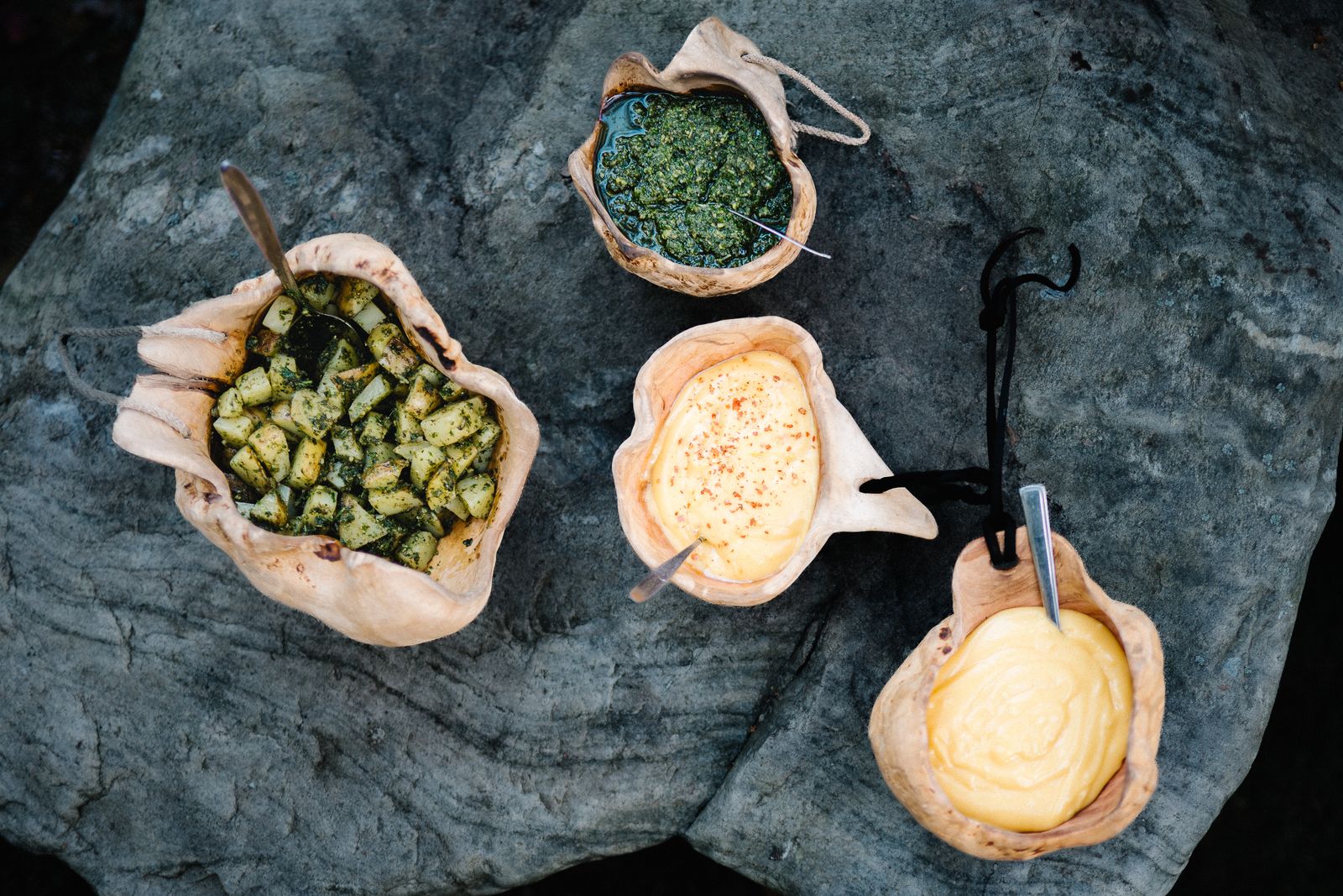 Bread bowls with herbs, salmon and cream laid out on a flat rock