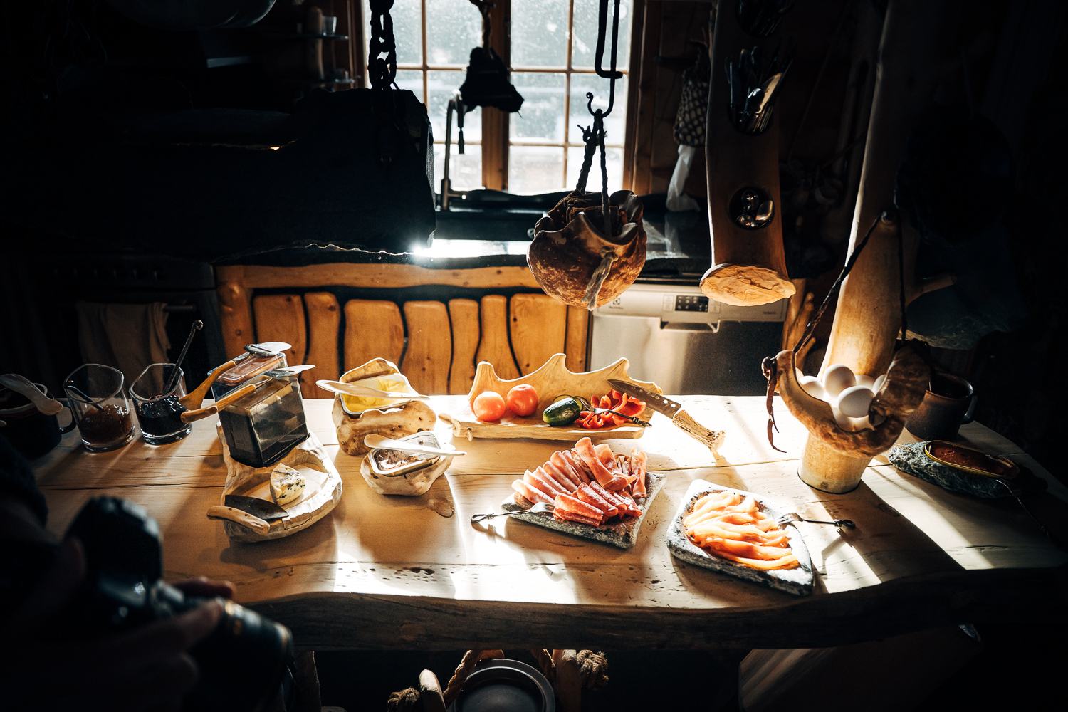 Breakfast laid out on a long wooden table in warm window light