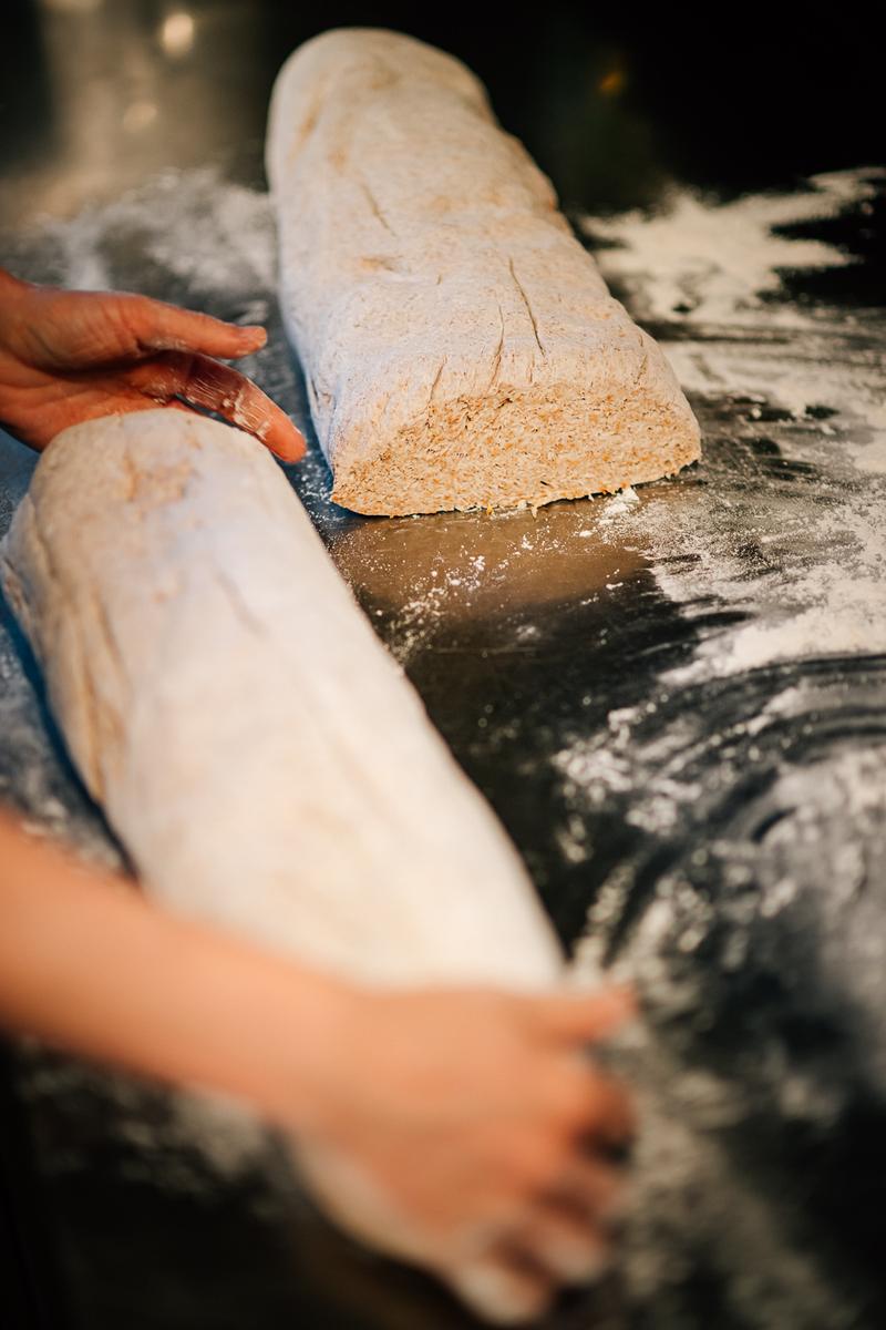 Hands shaping bread dough on a floured surface