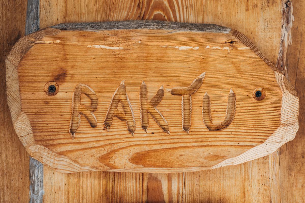 Hand-carved wooden sign reading RAKTU